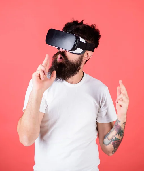 Man bearded hipster with virtual reality headset on red background. Shooting gallery VR. First person shooter shows how addictive VR could be. Man hand gesture as gun play shooter game in VR glasses
