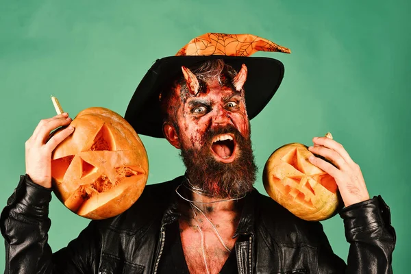 Hombre con maquillaje aterrador y sombrero de brujas sostiene calabazas — Foto de Stock