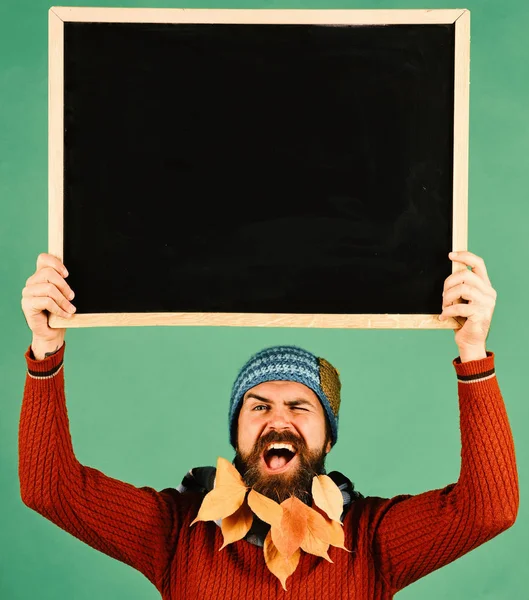 Man met hoed houdt schoolbord op groene achtergrond — Stockfoto