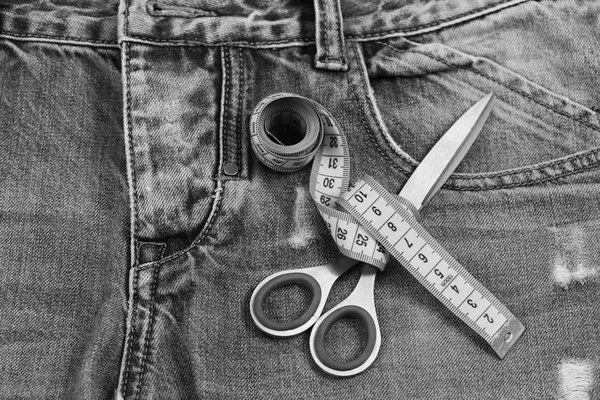 Meça a fita em volta da tesoura metálica no tecido de calça — Fotografia de Stock