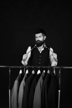 Yelekli sakallı adam elbise rafında..