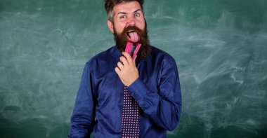 Okul kırtasiye. Öğretmen adam pembe zımba kara tahta arka plan ile sakallı. Okul kaza önleme. Yenilikçi öğretmen formal giyim kravat zımba tutar. Adam pis kullanmak zımba tehlikeli yol