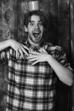 Duvarda bardağı tutan yakışıklı adam ve tahta arka plan.