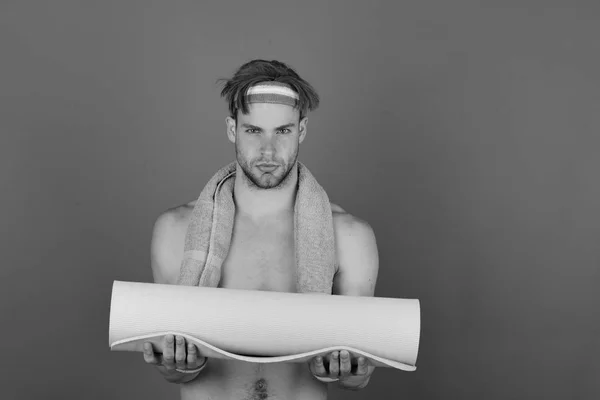 Uomo con torso nudo tiene tappetino yoga su sfondo viola — Foto Stock