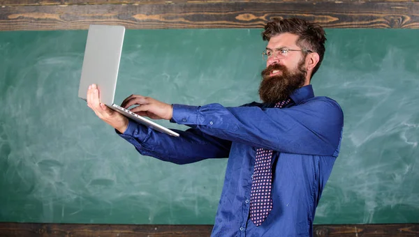 Concept d'enseignement à distance. Professeur barbu homme avec ordinateur portable moderne passé test en ligne tableau arrière-plan. Lunettes de vue professeur Hipster détient ordinateur portable passé contrôle des connaissances de distance. Passer le test en ligne — Photo