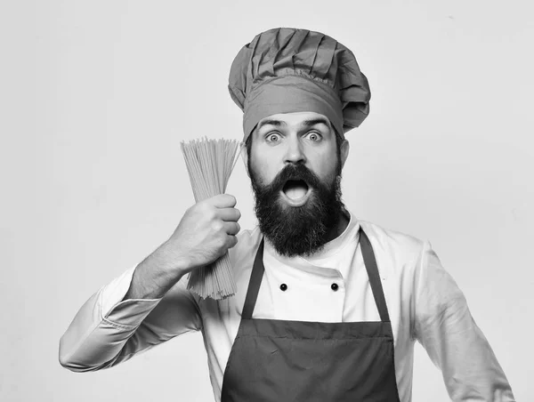 Hombre con barba aislada sobre fondo blanco. Chef sostiene espaguetis — Foto de Stock