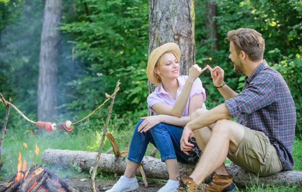 Couple tourists hold gesture while sit log bonfire. Man and girl play hand game. Couple play hand game. Hand gesture game decide who win. Play while wait roasting food. Reconciliation gesture — Stock Photo, Image