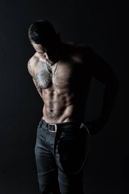 Dövmeli kol ve göğüs ile sporcu. Sakallı adam gömleksiz fit vücut'la. Dövme tasarım cilt üzerinde olan adam. Manken üzerinde kot pantolon deri kemer koymak. Fitness ve spor, vintage filtre ile ilgilenmek