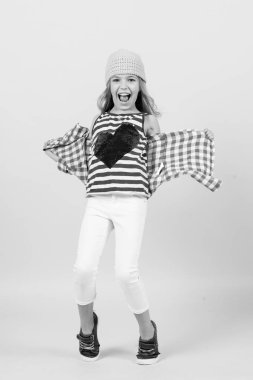 Sevgililer Günü konsepti. Gömleğinde kırmızı kalple gülümseyen bir kız. Turuncu arka planda mutlu bir çocuk. Çocukluk modası, güzellik, tarz. Yumruk pastel trend