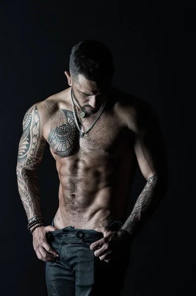 Homem de moda com tatuagem tirar jeans. Homem stripper mostrar torso sexy. Desportista com seis maços e abdominais. Atleta com músculos bíceps e tríceps. Desejo e atração, filtro vintage — Fotografia de Stock