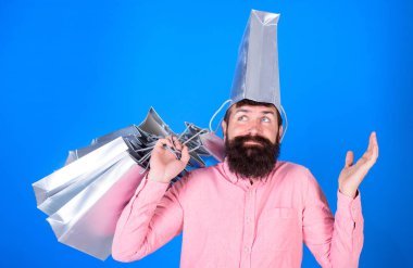 Adam sakal ve bıyık taşır alışveriş torbaları, mavi arka plan ile. Alışveriş kavramı. Kafasında torba ile deamy yüzündeki hipster bağımlısı Alışverişkoliğin var. Adam satış sezon indirimleri ile alışveriş