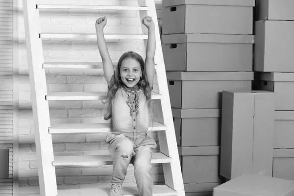 Merdivenleri ve kutuları olan neşeli yüzlü bir kız. — Stok fotoğraf