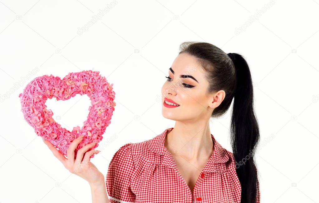 Woman in stylish dress holds symbol of love and smiles.