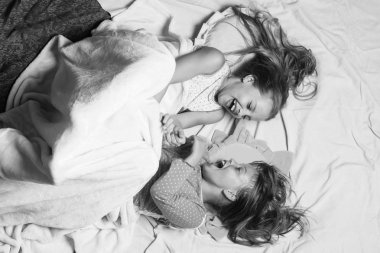 Gülen yüzlü çocuklar pembe arka planda yatıyor.