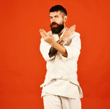 Kırmızı arka planda beyaz kimonolu sakallı adam.