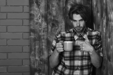 Duvarda bardağı tutan yakışıklı adam ve tahta arka plan.