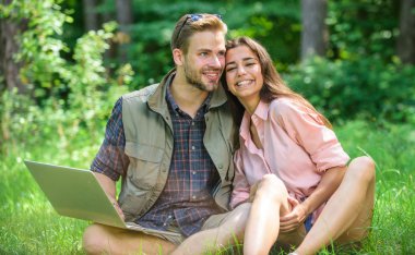 Modern teknolojileri herhangi bir çevre koşullarında çalışmak için fırsat verir. Adam ve yeşil çayır laptop ile çalışan kız. Çift gençlik eğlence dizüstü bilgisayar ile açık havada harcamak. Serbest fırsat