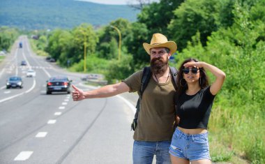 Gezginler araba durdurmaya. Otostop seyahat ucuz yollarından biridir. Çift otostopçu yaz güneşli gün seyahat. Çift yolcuları adam ve kız, otostop yol doğa arka plan kenar