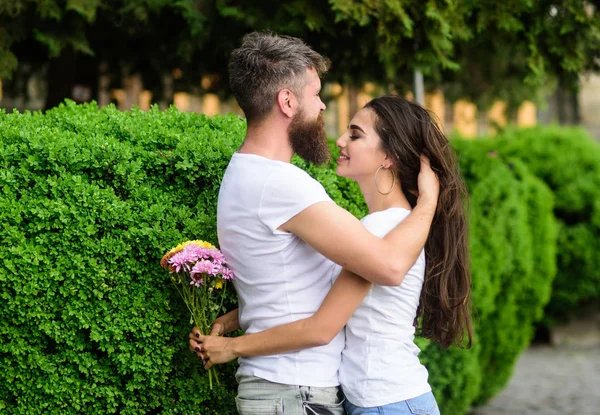 He will never let her go. Man fall in love with gorgeous girl. Man bearded hipster hugs woman. Strong romantic feelings become true love. Couple in love hugs on date in park green bushes background