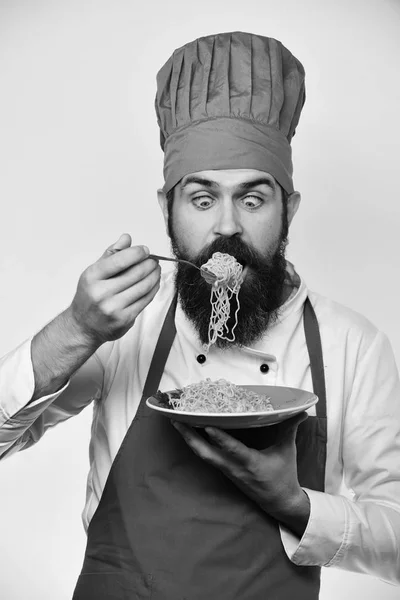 Le chef mange des nouilles italiennes ou asiatiques. Homme barbu — Photo