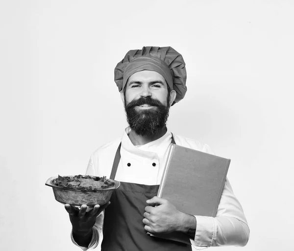 Cook med stolt leende i vinröd uniform håller bakad maträtt — Stockfoto