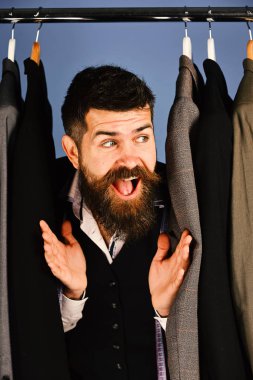 Mavi arka plan üzerinde özel ceketler yakınındaki meraklı gülümsemeyle terzi.