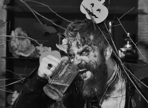 Halloween party concept. Man wearing scary makeup holds beer