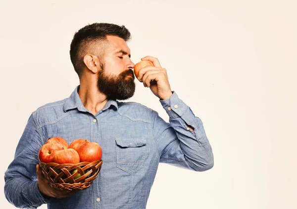 Sakallı adam elma meyveli hasır kaseyi tutuyor.