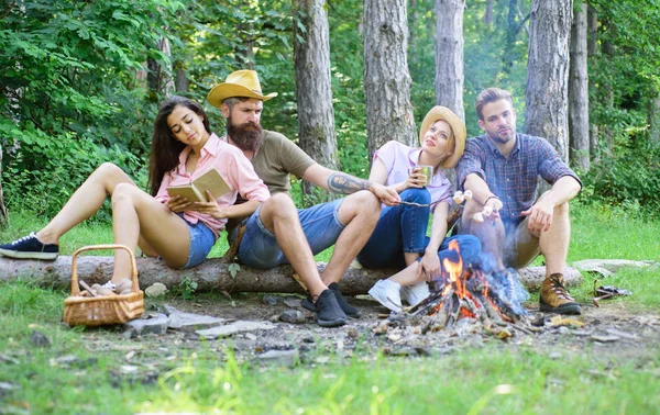 Youth hiking vacation. Hikers spend leisure in forest nature background. Hikers organized quick picnic to eat and relax. Hike picnic ideas. Hikers sit near campfire relaxing while wait roasting food