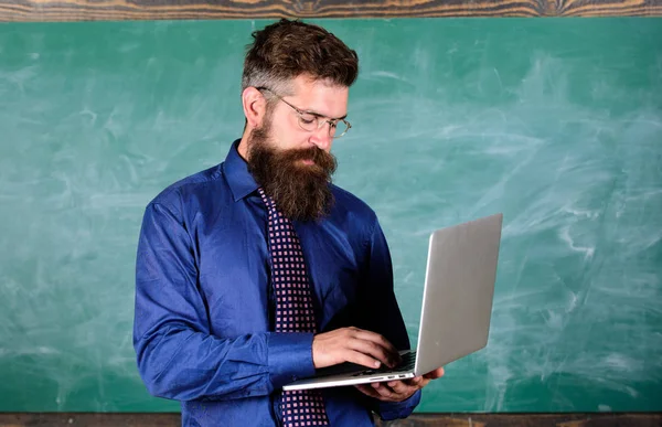 Professeur barbu homme avec fond moderne tableau noir ordinateur portable. Éducation en ligne. Éducation aux technologies modernes. Professeur hipster porter des lunettes et cravate tient ordinateur portable. Éducation aux technologies numériques — Photo