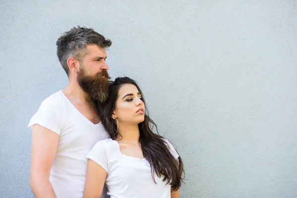 Couple friends hang out together. Young and stylish. Youth stylish outfit simple but modern. Couple white shirts cuddle near grey wall. Hipster bearded brutal and stylish fashionable girl hang out
