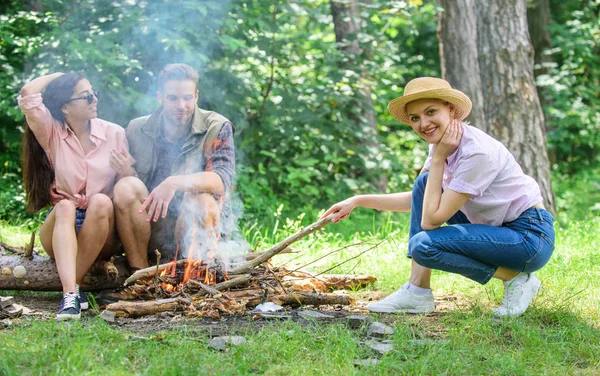 Friends hang out near bonfire picnic. Company youth camping forest prepare bonfire for picnic. Add some wood to fire. Company friends or family making bonfire in forest nature background