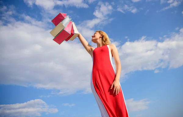 Поради щодо успішного продажу літа. Жінка червона сукня піднімає букетні сумки на фоні блакитного неба. Не соромтеся купувати все, що забажаєте. Свобода вибору. Дівчина задоволена покупками — стокове фото