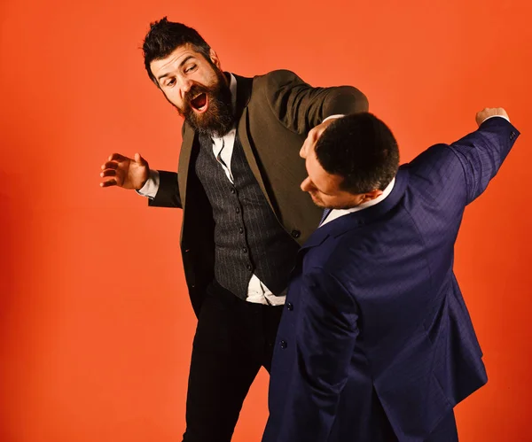 Business fight concept. Businessman with raging face hits and punches opponent.