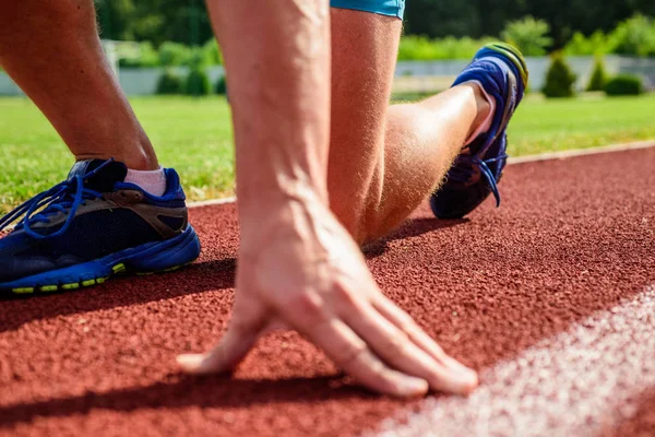 Flexibiliteit is de mogelijkheid om het uitrekken van gezamenlijke te beperken van verkeer van de reeks. Gezamenlijke zorg voor hardlopers. Hand van sportman op atletiekbaan lage beginpositie. Loper klaar om te gaan close-up. Ultieme rechtsmiddelen — Stockfoto