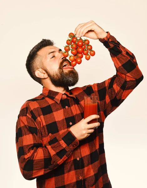 Guy κρατά homegrown συγκομιδή. Άνδρας με γενειάδα κρατά ποτήρι χυμό και τρώει λαχανικά — Φωτογραφία Αρχείου
