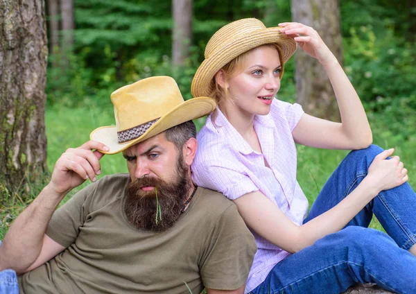 Wearing sun hats protect head and hair from sun. Choose proper clothing and equipment to hike and forest picnic. Couple in straw hats sit meadow relaxing. Reasons you should definitely wear more hats