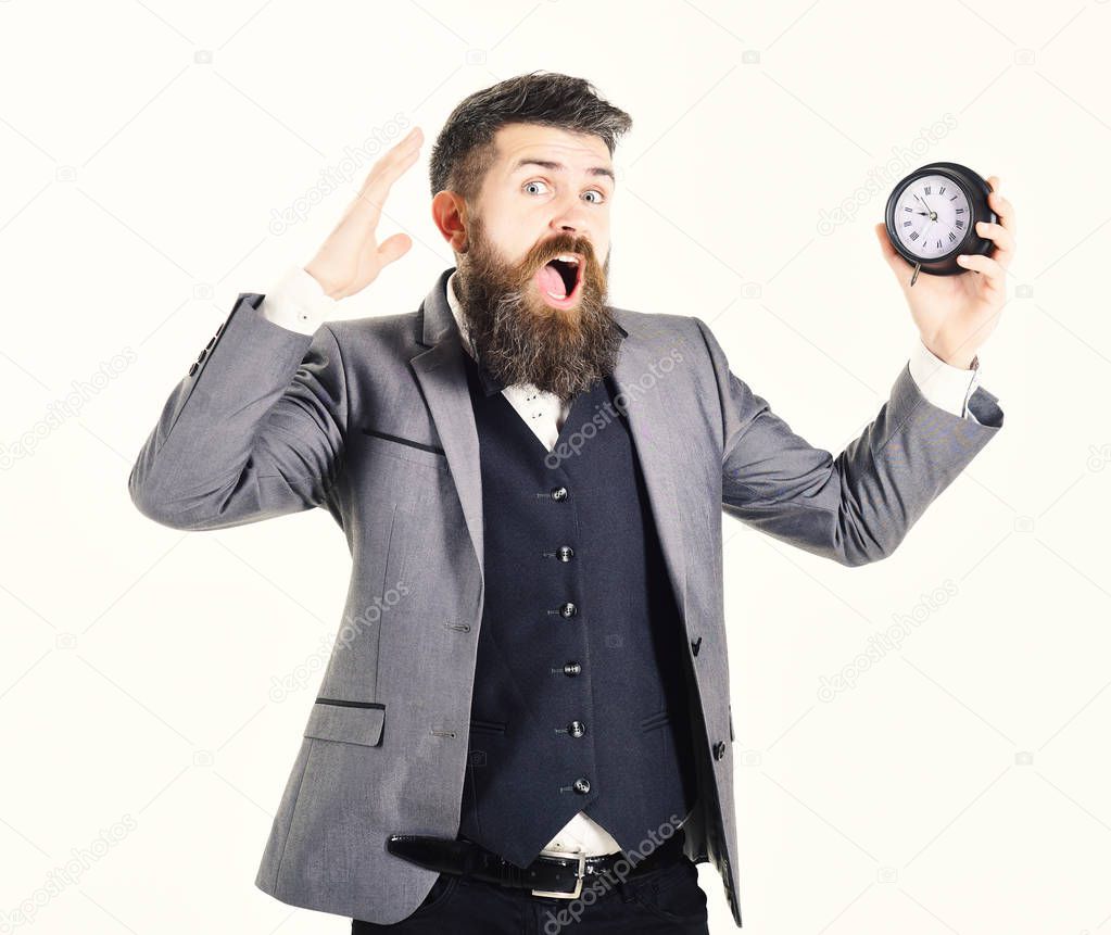 Bearded man holds clock and screams. Clock, too busy, lack of time, timeless, hurry, no time business, stress concept. Mature man with long beard and scared face. Businessman has lack of time
