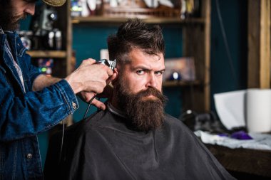 Şık saç kesimi kavramı. Eller berberin kesme makinesi ile kapatın. Hipster sakallı istemci üzerinde katı yüz saç modeli almak. Berberler saç kesme makinesi kırpma ile ver. İstemci salon zemin üzerine sakallı