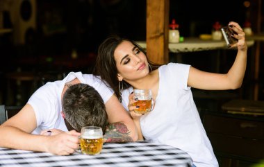 Utanç verici anı yakalamak. Adam sarhoş uykuya tablo ve tam bira Bardagı kızla. Kız sarhoş erkek arkadaşıyla selfie fotoğraf çekiyorum. O onun için çok zayıf görünüyor. Sarhoş arkadaşım dalga kadın
