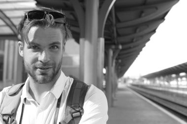 Gülen yüz ve sırt çantası, kopya alanı ile turist. Cevapsız tren ve kavram seyahat. Genç platform üzerinde duran adam