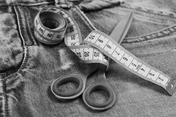 Confección de ropa y concepto de diseño. Medir la cinta enrollada alrededor de tijeras de metal como concepto de ropa — Foto de Stock