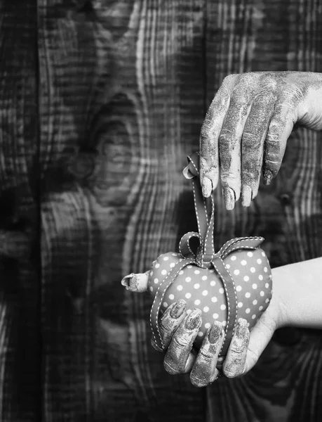 Mano femenina untada en pintura dorada o glister sosteniendo lunares rosados hechos a mano corazón de San Valentín sobre fondo marrón vintage estudio, enfoque selectivo. —  Fotos de Stock