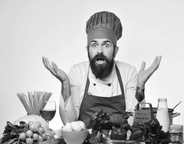 Concept végétarien, diététique et culinaire. Chef masculin étonné ou cuisinier avec barbe près des légumes — Photo