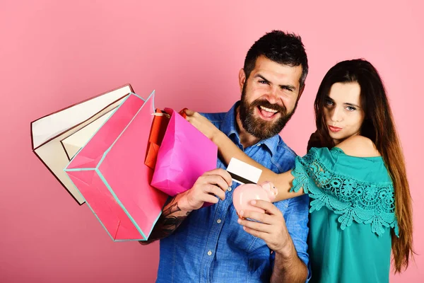 Sakallı kredi kartı ve kumbara, kopya alanı tutar. Aşık çift alışveriş torbaları, pembe arka plan tutar..