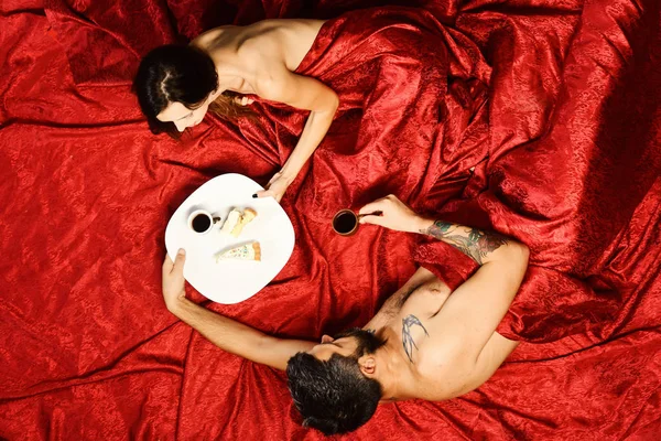 赤いシートに愛のカップル。完璧な朝と愛の概念。ひげを持つ男は、ベッドで女性のロマンチックな朝食 — ストック写真