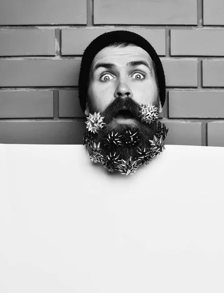 Paper sheet on brown brick wall studio background. Bearded man, brutal caucasian surprised hipster with gift decoration stars — Stock Photo, Image