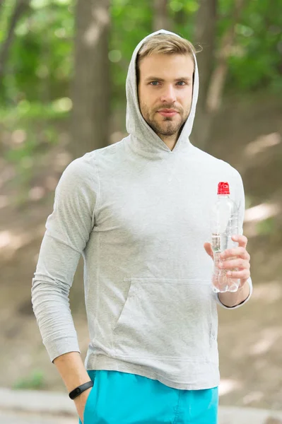 Harika bir egzersizden sonra vitamin içeceğini tazeliyorum. Adam atletik görünüşte su şişesi tutuyor. Sporcu parktaki eğitimden sonra su içer. Sporcu erkek sporcu idmandan sonra şişeye su döker. — Stok fotoğraf
