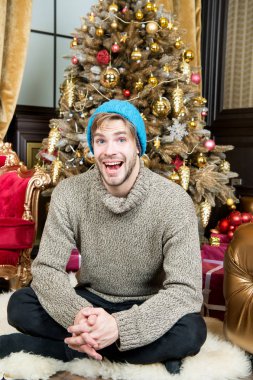 Xmas ağacı odasında tüylü halı üzerinde maço gülümseme