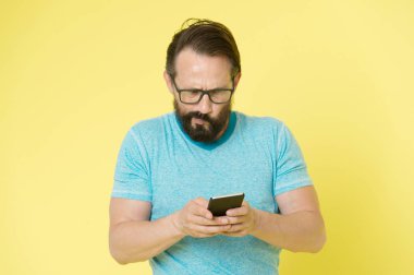 Gözlüklü adam kafası karışmış, akıllı telefon kullanıyor. İnsan kullanıcısı uygulama akıllı telefonuyla etkileşim kurar. Sakallı, olgun etkileşimli mobil arayüz uygulaması. Olgun insanlar için dijital cihazlara alışmak zor.